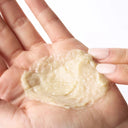 Close-up of a hand holding a creamy, textured K-beauty skincare product, showing its rich, exfoliating consistency against a clean white background.